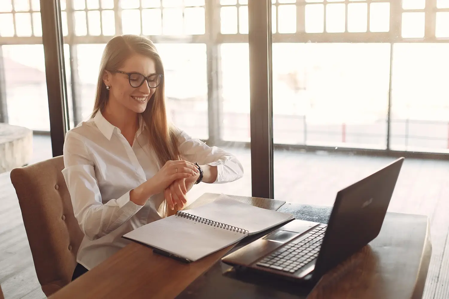 Smiling woman entrepreneur checking time on her watch